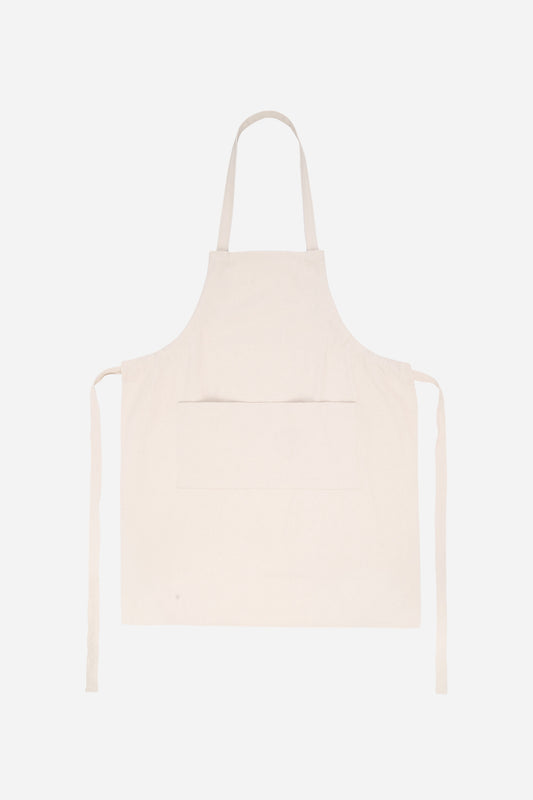 Flat lay of Adjustable Apron in Natural with straps untied positioned to the sides of the apron.