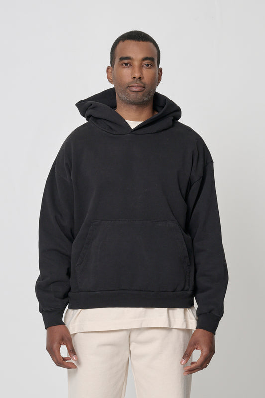 Front view: 6'2" man wearing Black Trash Hoodie in size XL. Hem hits his middle hip.