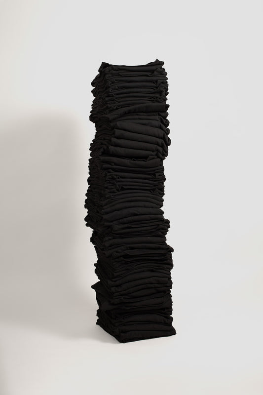 Stack of fifty folded Long Sleeve Trash Tees in Black against a blank backdrop.