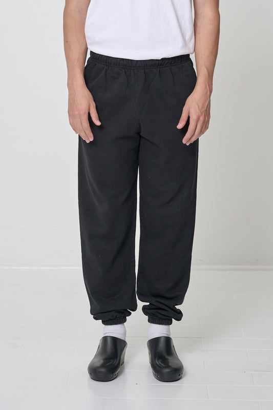 Front view: 6' person in size M Black Trash Sweatpants, relaxed fit, bunching at the ankles.