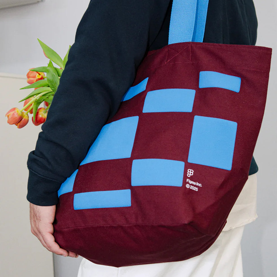 Person holding a custom maroon Big Tote with blue geometric patterns, featuring a brand Figma Inc logo.