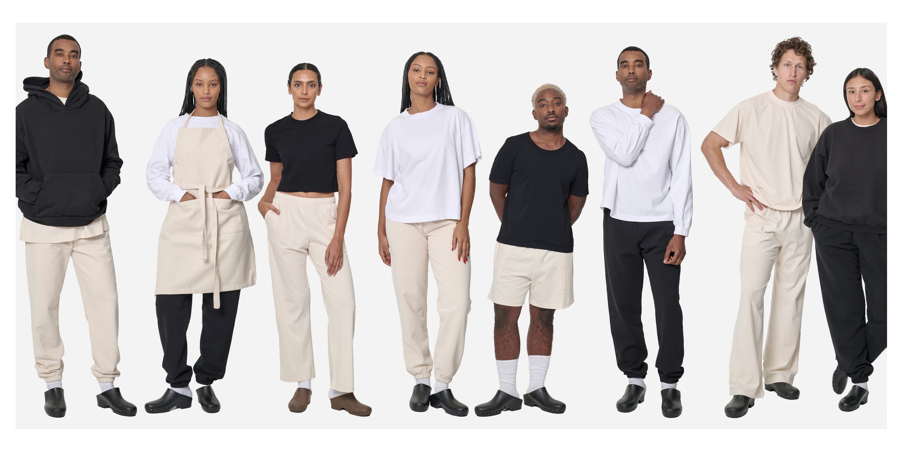 Eight people wearing a variety of Everybody.World wholesale garments in Scour, White, and Black on a white background