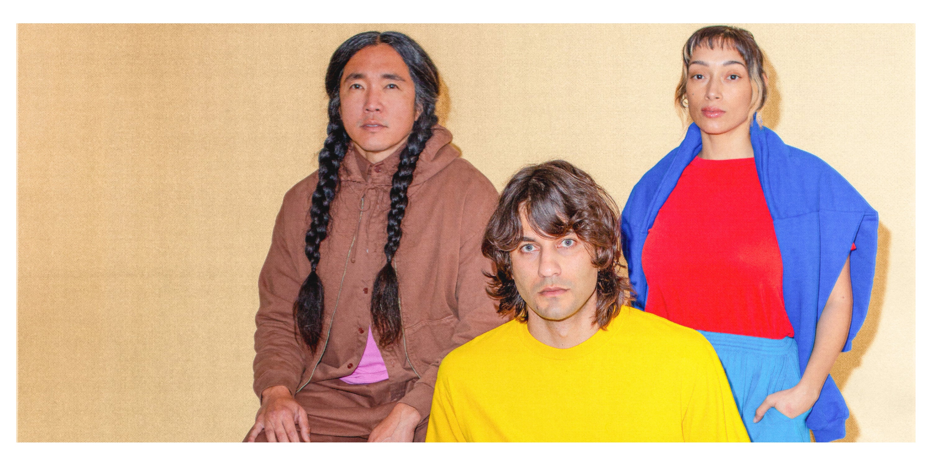 Three people in colorful Trash Collection clothing posing against a beige background