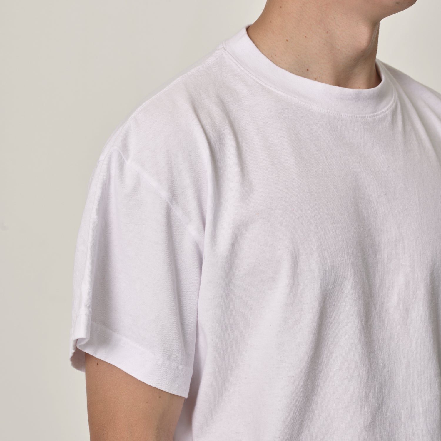 A person wearing a white Trash Tee showing the details of the sleeve and collar.
