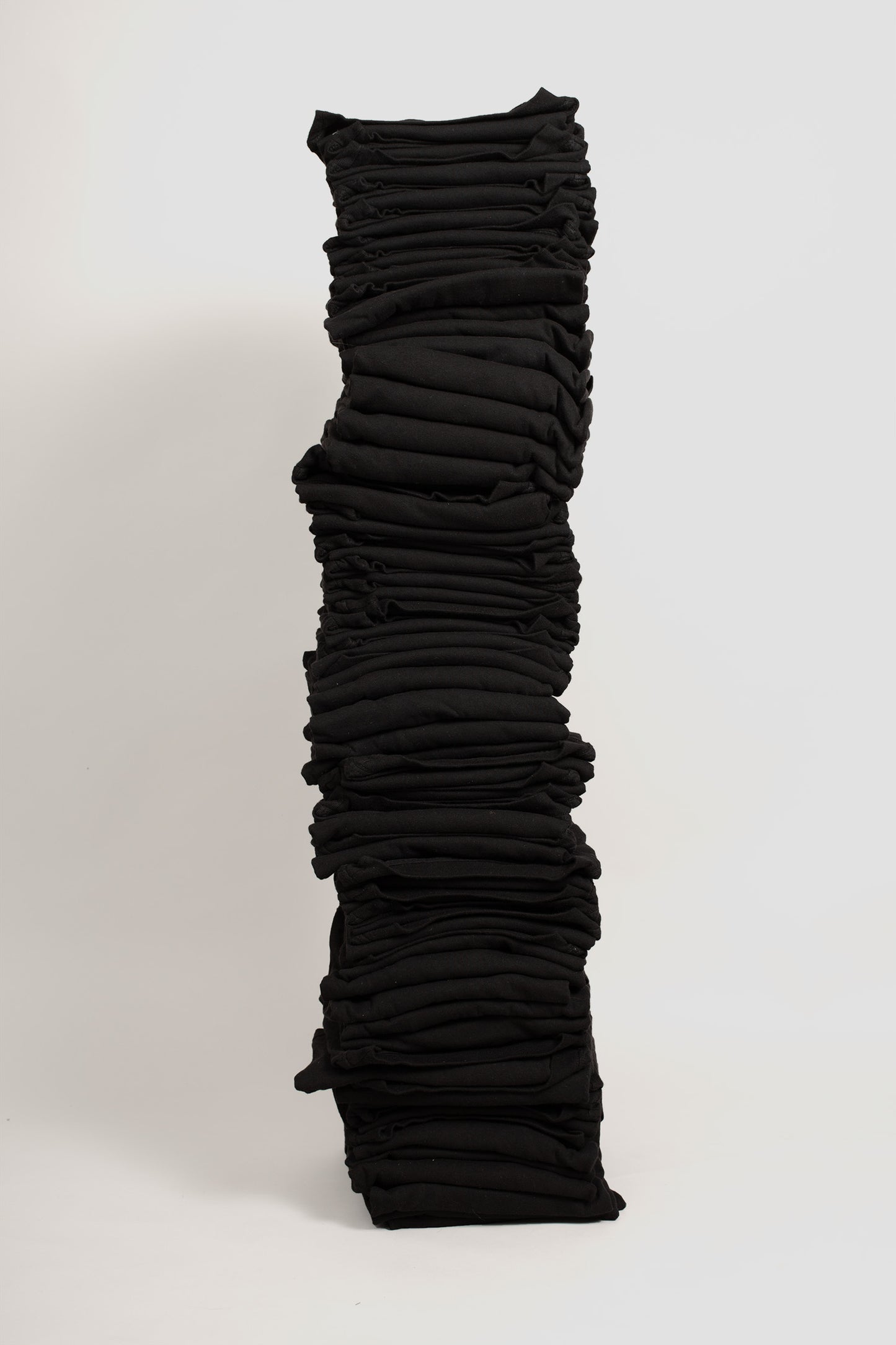 Stack of sixty folded Boxier Trash Tees in Black against a plain background.