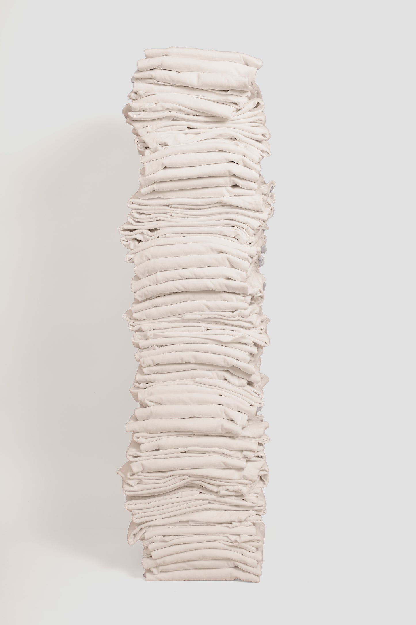 Stack of sixty folded Boxier Trash Tees in Scour against a plain background.