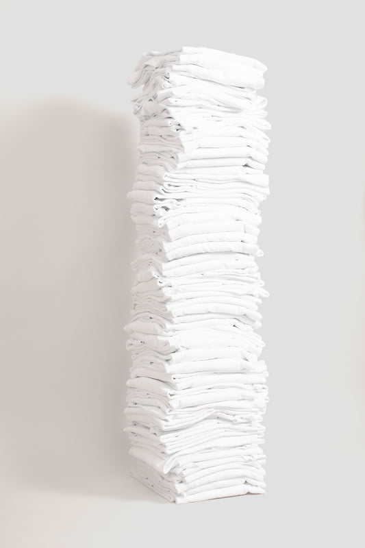 Stack of sixty folded Boxier Trash Tees in White against a plain background.