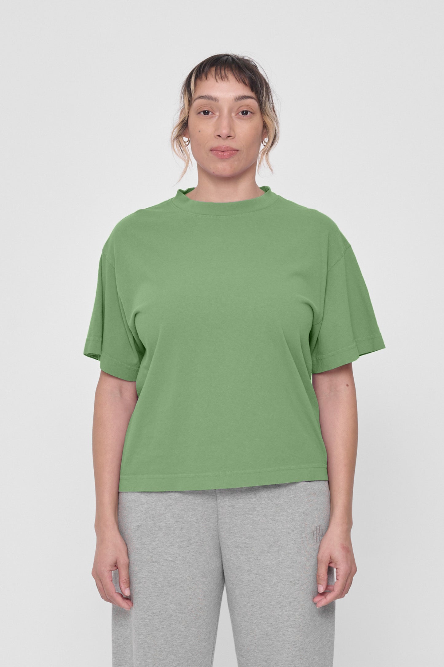A woman in a Fox Green Boxier Trash Tee. Hem ends just above the hip.