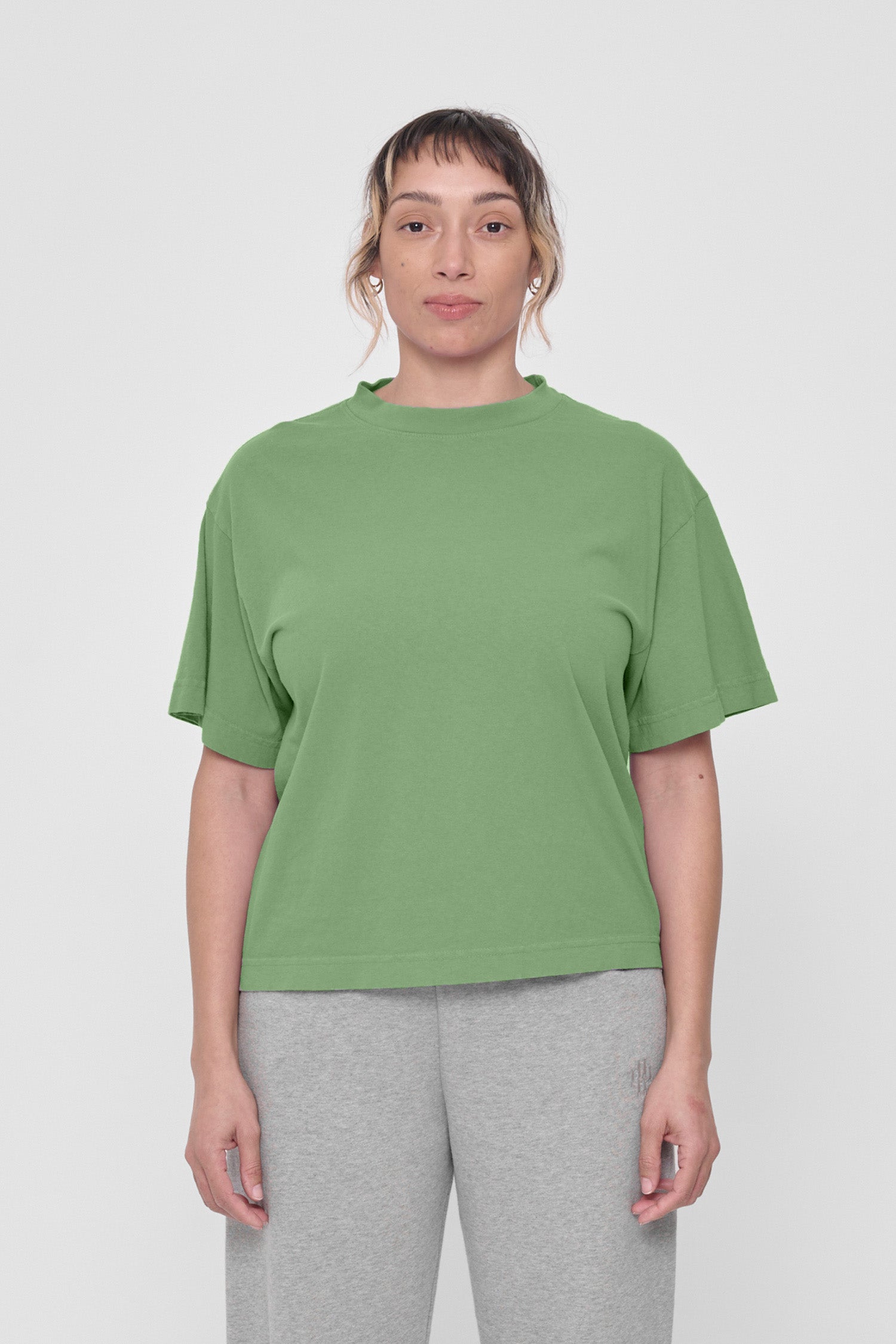 A woman in a Fox Green Boxier Trash Tee. Hem ends just above the hip.