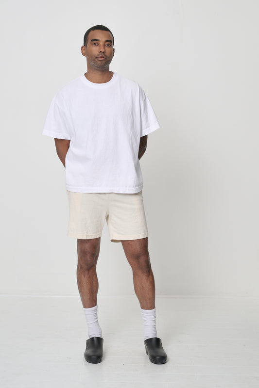 A man wearing a White Boxier Trash Tee with Scour Everyday Shorts for casual styling.