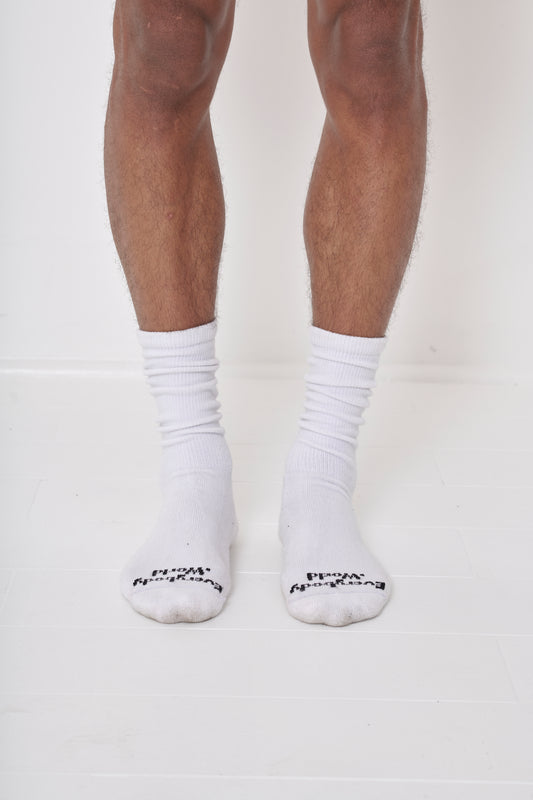 White Squishy Socks, branded 'Everybody.World' in black, at the toe, shown on a person's lower legs.