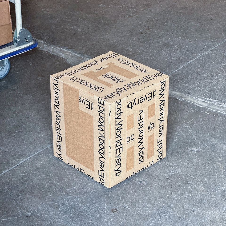 Cardboard box with 'Everybody World' written on the tape, on a concrete floor.