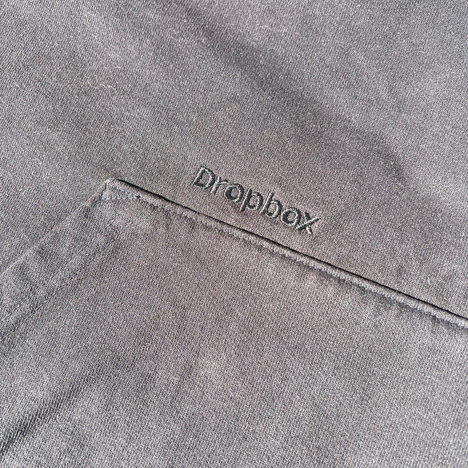 Close up of custom gray Trash Hoodie pocket with Dropbox logo embroidered.