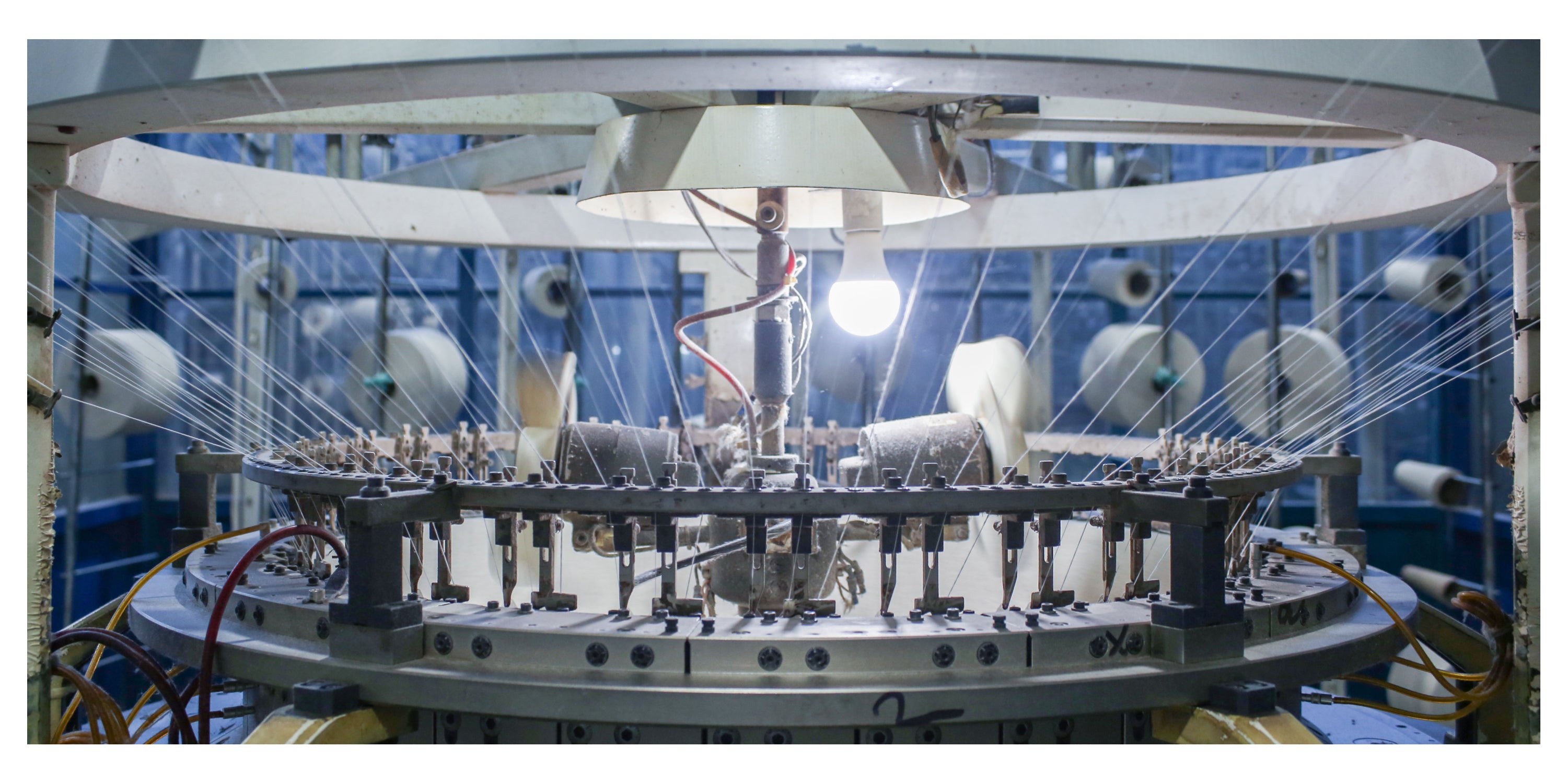 Close up on part of a cotton knitting machine with a light bulb on.