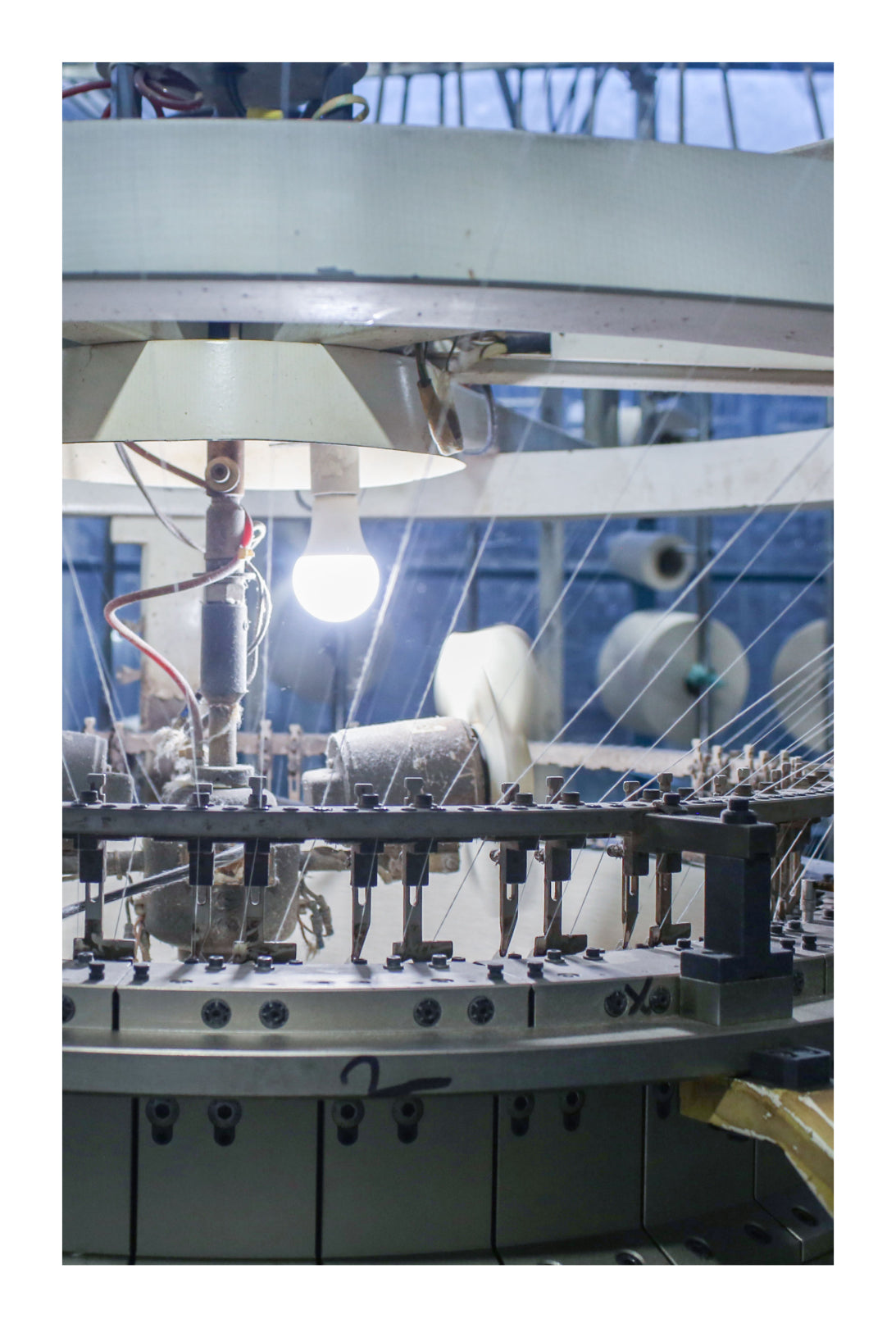 Close up on part of a cotton knitting machine with a light bulb on.