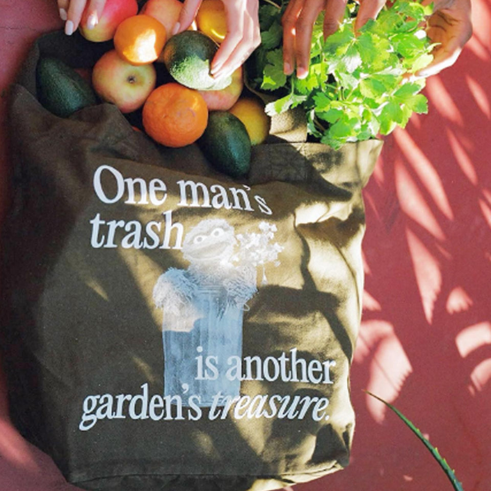 Custom green Big Tote with text 'One man's trash is another garden's treasure' filled with fruits and vegetables.