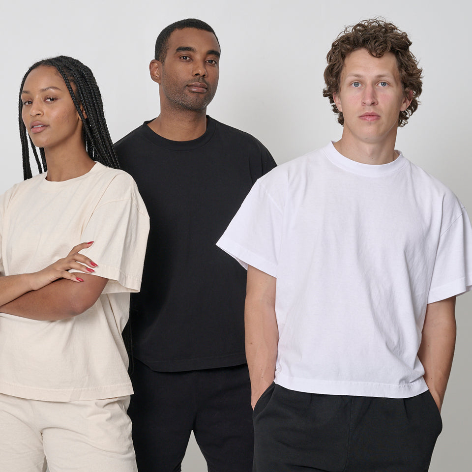 Three people wearing Boxier Trash Tees in Scour, Black, and White. 