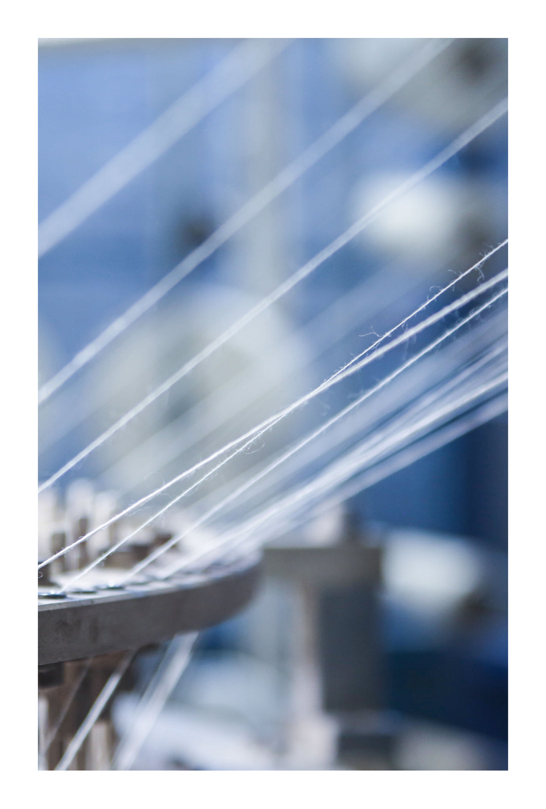 Close-up of a cotton threads strung through a knitting machine.