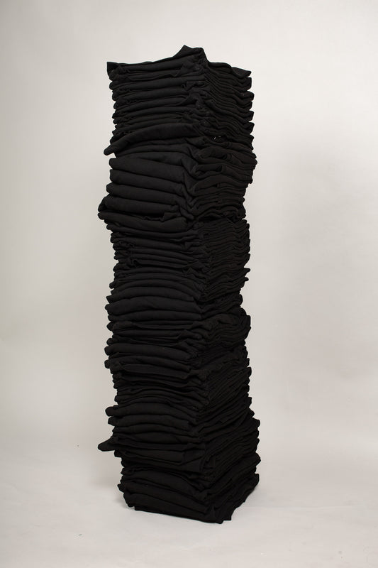 Stack of sixty folded Short Sleeve Trash Tees in Black against a plain background.