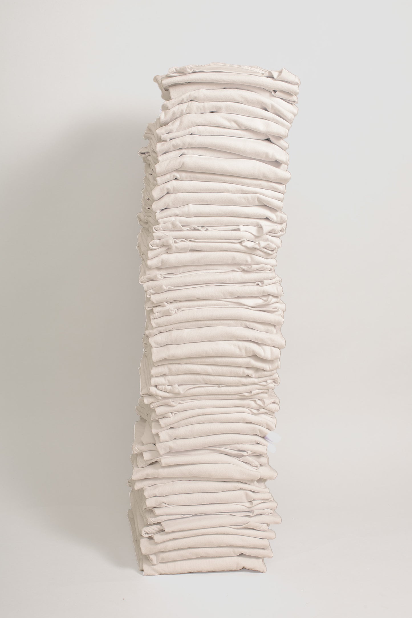 Stack of sixty folded Short Sleeve Trash Tees in Scour against a plain background.