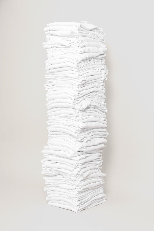 Stack of sixty folded Short Sleeve Trash Tees in White against a plain background.